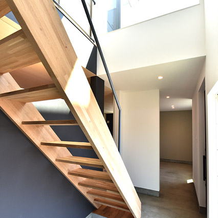 住まいの中心となる吹き抜け階段は、木、塗装、土間コンクリートなど多彩な素材の組み合わせが美しい空間。